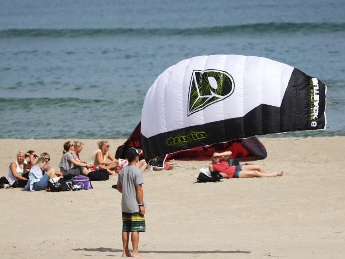 a group of people sitting at a beach umbrella in the sand