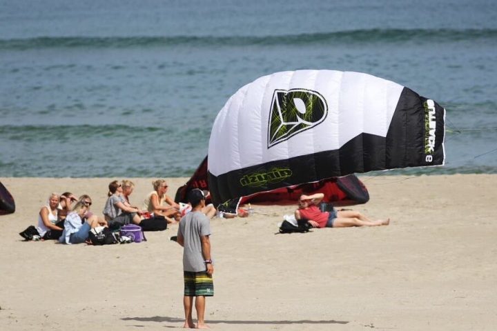 a group of people sitting at a beach umbrella in the sand
