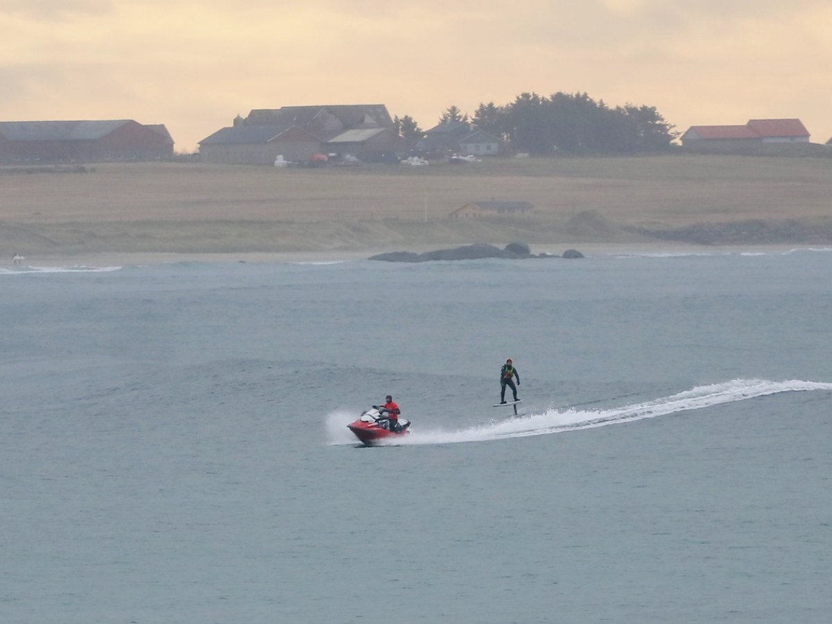 a group of people riding on the back of a boat in the water
