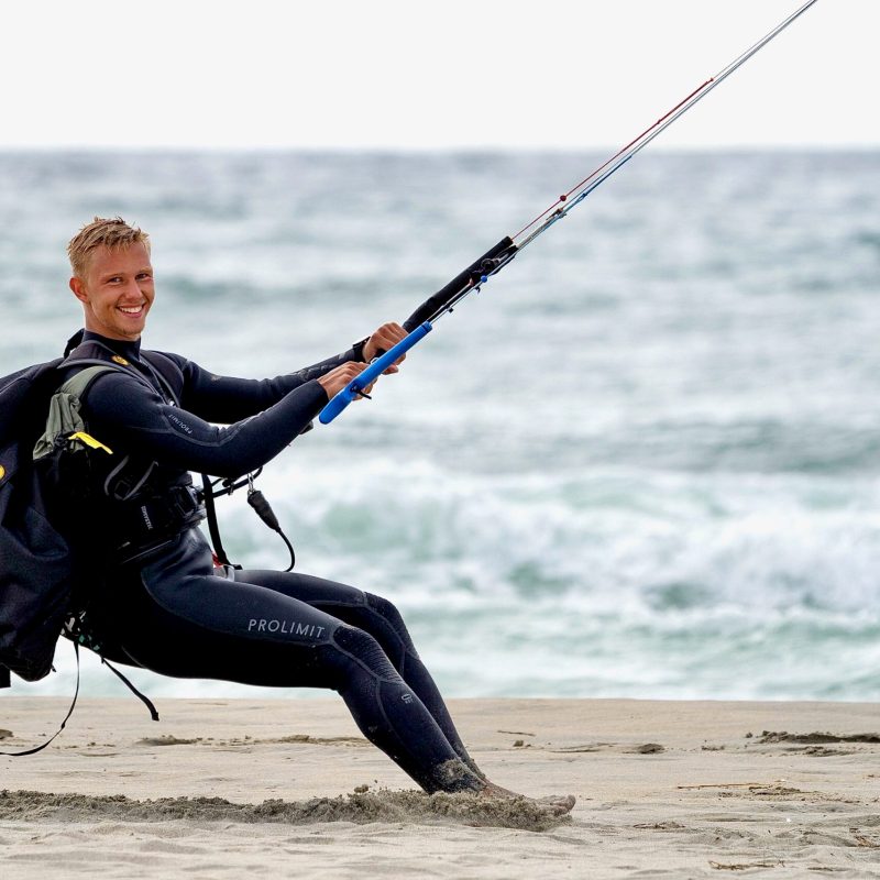 a man in a wet suit on a beach near a body of water
